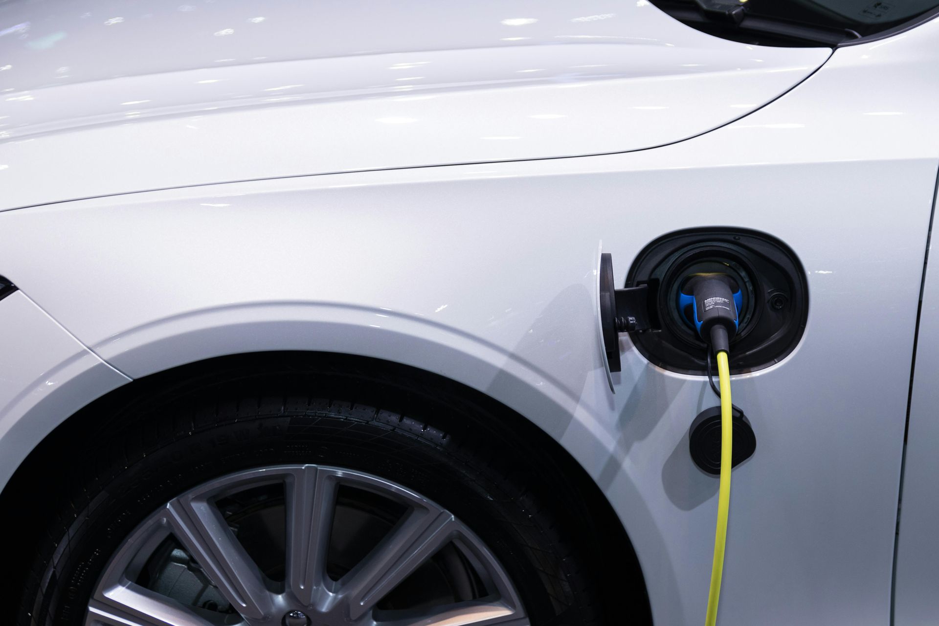 White electric car charging, cable connected to port on the front panel.